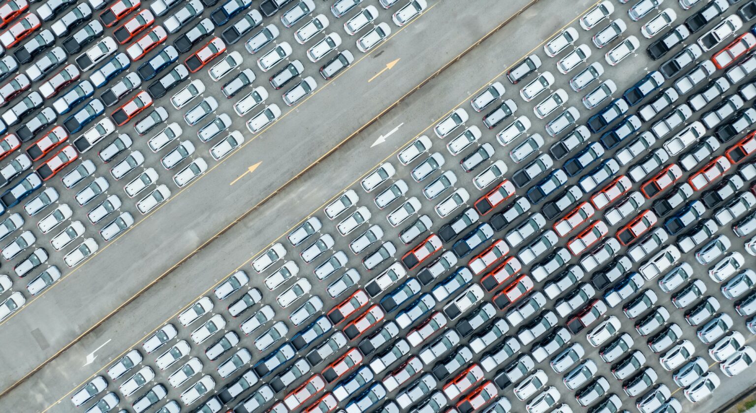Aerial view of new cars stock at factory parking lot. Above view many cars parked in a row.